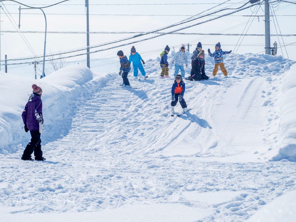雪を積み上げたマウンドでスキーをする園児たち