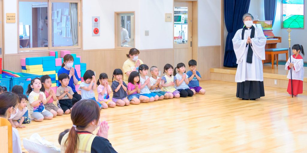 礼拝でお祈りをするチャプレンと園児たち