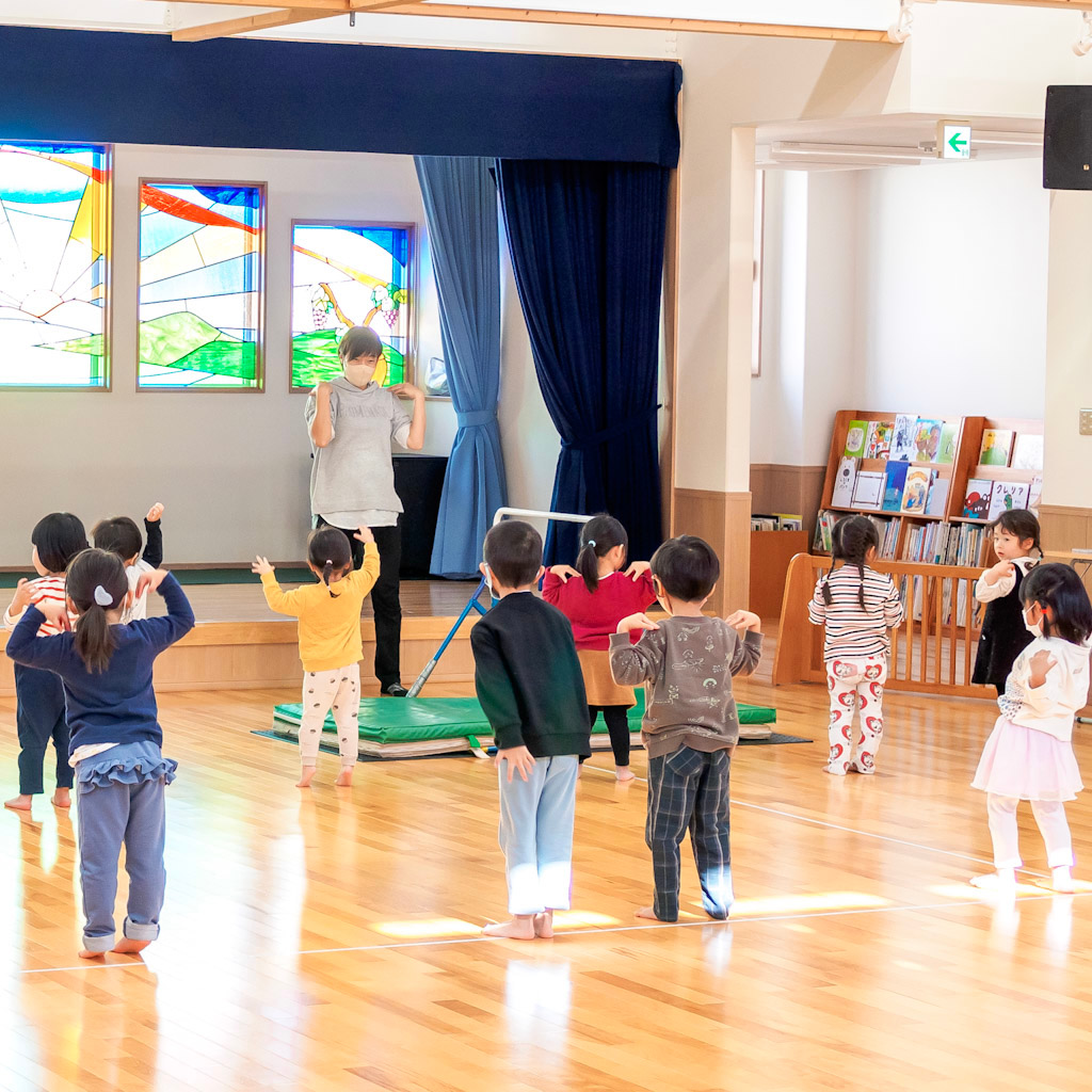 ホールでラジオ体操をする園児たち