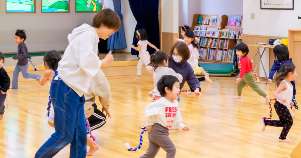 しっぽ取りゲームをする子どもたちと保育士